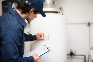 A plumber looks at a water heater gauge.